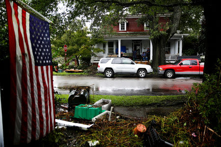 An American flag hangs across the street as people clean their house after the passing of Hurricane Florence in New Bern, North Carolina, U.S., September 16, 2018. REUTERS/Eduardo Munoz