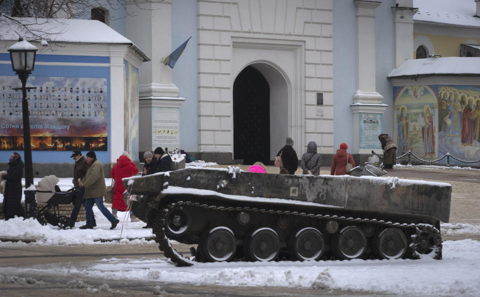 People pass by the entrance to St.Michael Cathedral, with a damaged Russian military vehicle in the foreground, in central Kyiv, Ukraine, Monday, Dec. 12, 2022. Ukraine has been fighting with the Russian invaders since Feb. 24 for over nine months. (AP Photo/Efrem Lukatsky)