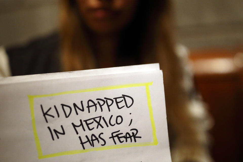 In this Tuesday, Nov. 5, 2019, photo, Lizbeth poses for a portrait in a relative's home behind a page from her court documents in Tijuana, Mexico. Lizbeth, a Salvadoran woman seeking asylum in the United States, never thought she would be returned to Mexico to wait for the outcome of her case, after suffering multiple assaults, and being kidnapped into prostitution on her journey through Mexico. Critics of the Trump administration's "Migrant Protection Protocols" policy, say it denies asylum seekers fair and humane treatment, largely by forcing them to wait in a country plagued by large pockets of drug-fueled violence, demonstrated this week by the slaughter near the U.S. border of several children and women. (AP Photo/Gregory Bull)