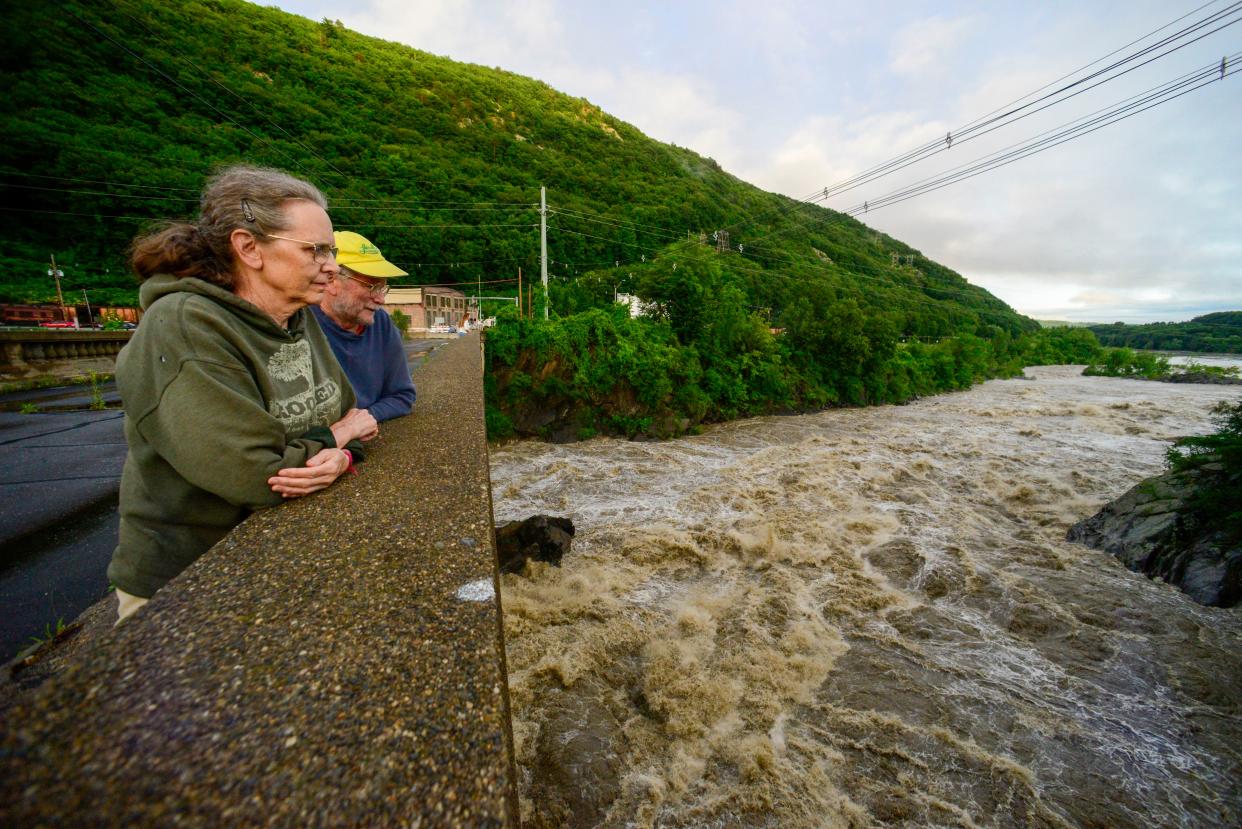 People stand on the Vilas Bridge, in Bellows Falls, Rockingham, Vt., to watch the water from the Connecticut River flow through on Monday (AP)