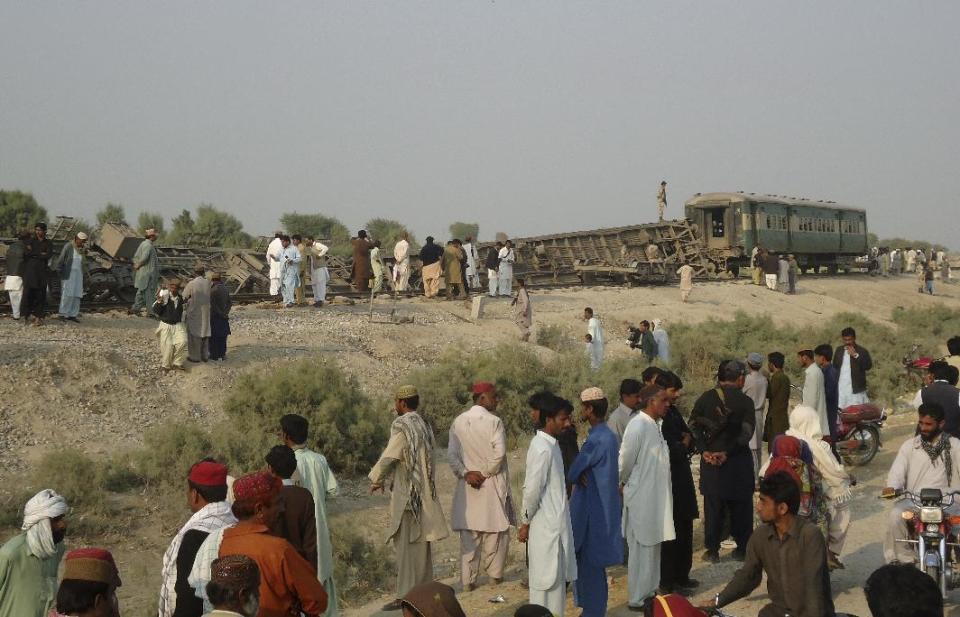 Pakistanis gather at the site of a deadly bomb blast that hit a train, in Kashmor district, Pakistan, Sunday, Feb. 16, 2014. A bomb placed by an ethnic separatist group derailed a train in southwest Pakistan on Sunday, killing several people including children, and wounding tens more police and the militants said. (AP Photo/Fida Hussain)