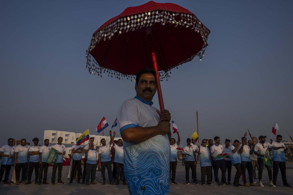 Aficionados de Indian, parte del grupo Thrissur Jilla Sauhrudavedi (TSJV), frente al reloj con la cuenta regresiva del Mundial Qatar 2022, en la Corniche de Doha, el viernes 21 de octubre de 2022. (AP Foto/Nariman El-Mofty)