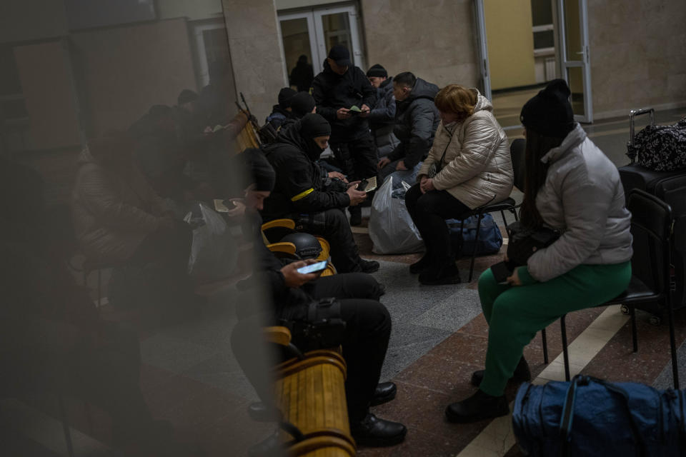 Ukrainian police conduct a security check on passengers before boarding the Kherson-Kyiv train at the Kherson railway station, southern Ukraine, Saturday, Nov. 26, 2022. Fleeing shelling, hundreds of civilians on Saturday streamed out of the southern Ukrainian city whose recapture they had celebrated just weeks earlier. (AP Photo/Bernat Armangue)