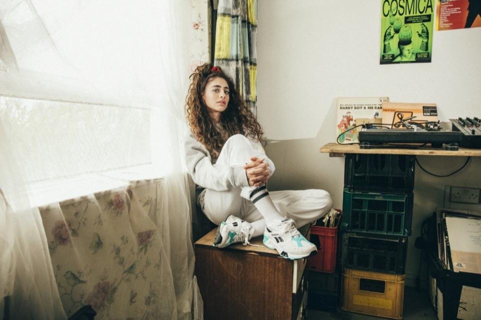 Woman sitting on a dresser and wearing Reebok apparel and sneakers