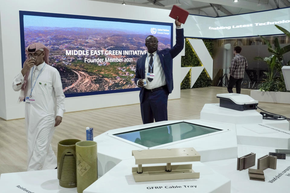 Delegates walk through the Saudi Arabia pavilion with a display for the kingdom's Middle East Green Initiative at the COP27 U.N. Climate Summit, Thursday, Nov. 10, 2022, in Sharm el-Sheikh, Egypt. (AP Photo/Nariman El-Mofty)