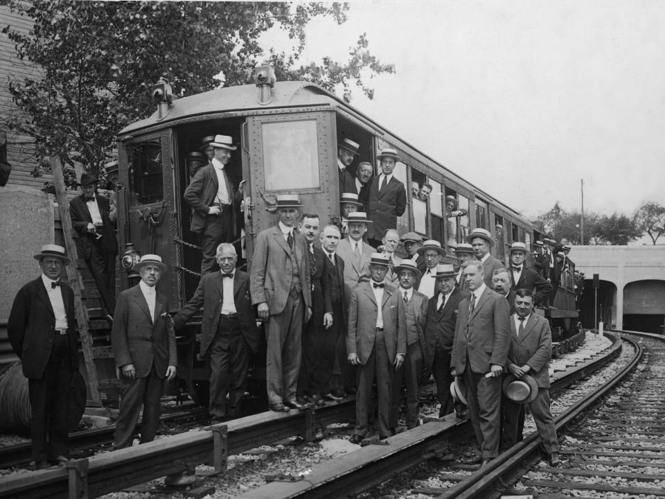 Officials of the Interborough and Public Service Commission stand in and a round a subway car on the IRT's Eastern Parkway Line. It's an above ground train