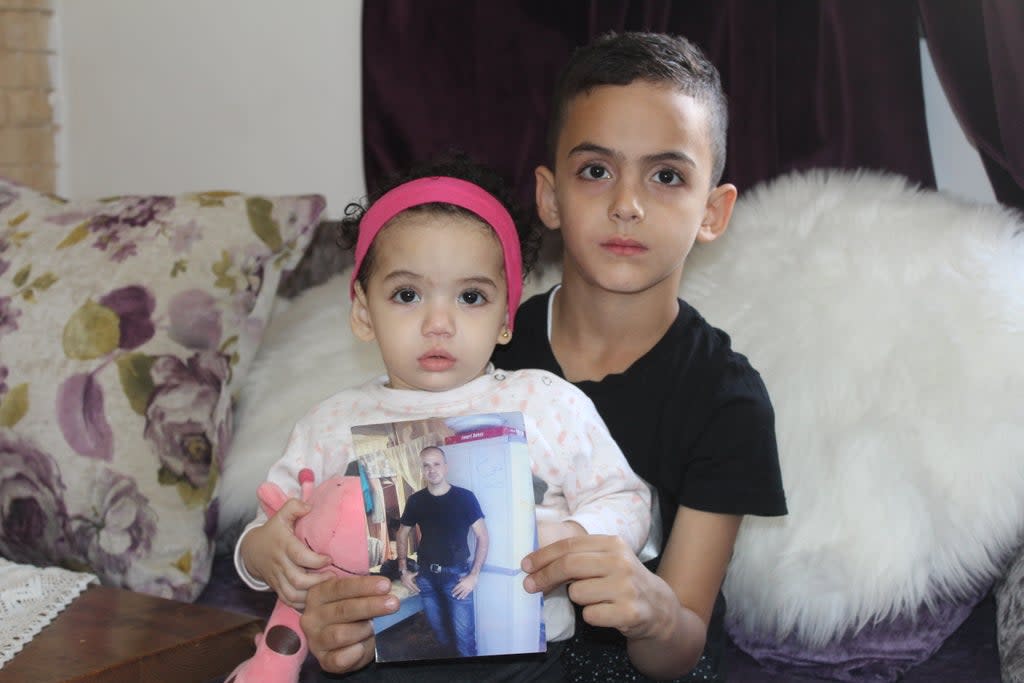  Son Mohammad and daughter Nour holding a photo of their father Shadi Abu Aker, currently detained by Israel (Courtesy of the family)