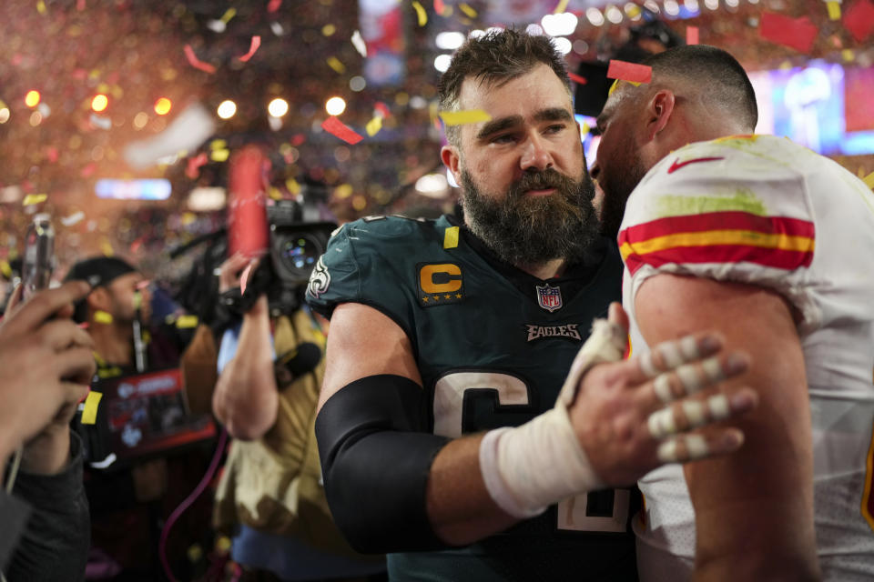 Two football players from opposing teams exchange a respectful head-to-head moment amidst post-game celebrations