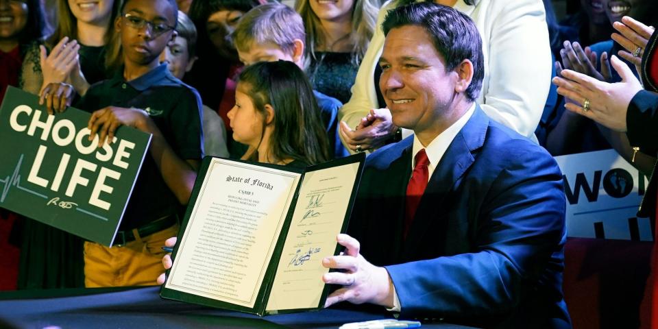 Florida Gov. Ron DeSantis holds up a 15-week abortion ban law after signing it, Thursday, April 14, 2022, in Kissimmee, Fla