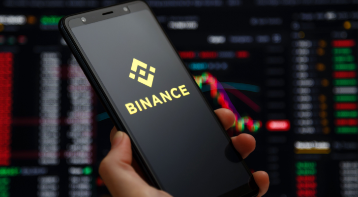 Binance mobile app running at smartphone screen with a trading page at background. Binance one of the world's leading cryptocurrency exchange and trading platform.