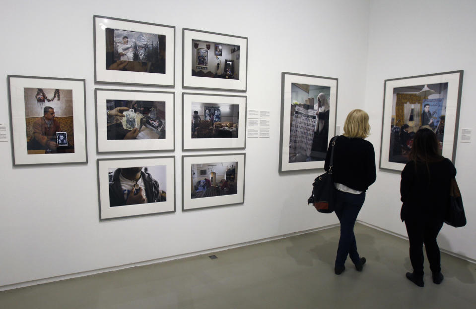 Visitors view photos by Palestinian photographer Ahlam Shibli, at the Jeu de Paume museum in Paris, Wednesday June 12, 2013. The exhibit which started last week at the Jeu de Paume, features dozens of photographs with captions that glorify dead members of Palestinian groups. (AP Photo/Remy de la Mauviniere)