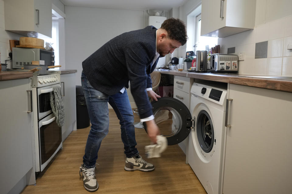 Dominic Watters, a single dad and founder of the Food is Care campaign, puts a towel in the washing machine at his home in Canterbury, England, Monday, June 10, 2024. Since calling a general election, British Prime Minister Rishi Sunak has been at pains to repeat a key message on the campaign trail: The economy is turning a corner, inflation is down, and things are looking up. That’s not the reality for millions across the U.K. still feeling the squeeze from high food, energy and housing prices. (AP Photo/Kin Cheung)