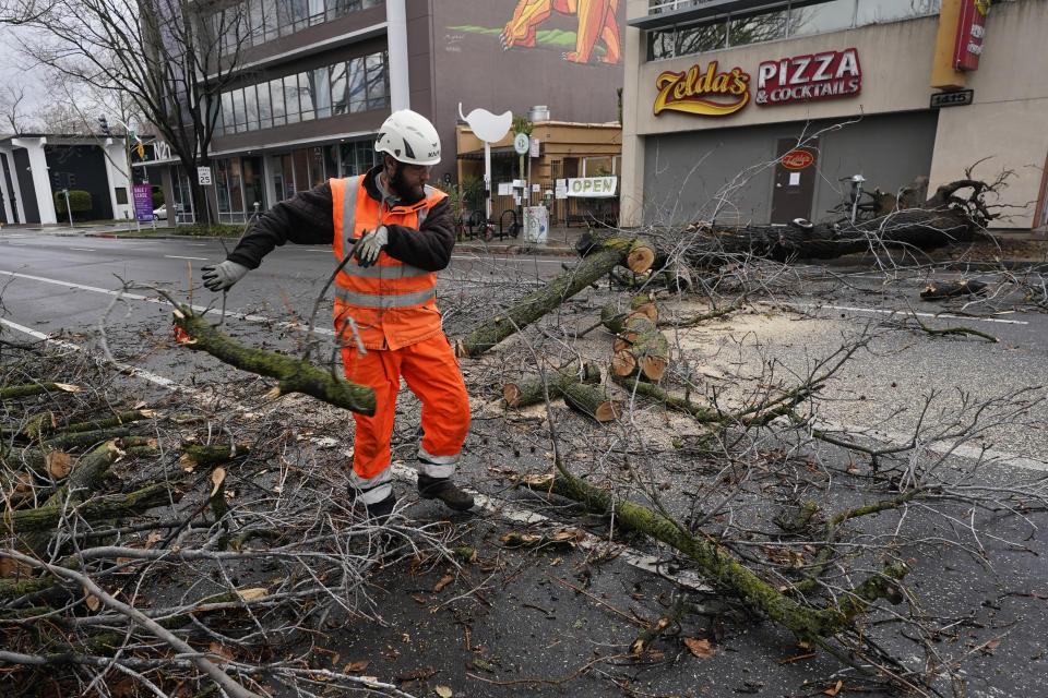 Sacramento City worker Kevin McClain moves a section of tree he cut up that was blown over by an overnight storm that swept through Sacramento, Calif., Wednesday, Jan. 27, 2021. (AP Photo/Rich Pedroncelli)