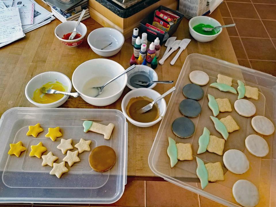 The glaze, which is simply confectioners’ sugar, milk and vanilla extract, is tinted using food coloring or gel dye and then applied to the cookies using small spatulas. The glaze dries hard overnight.