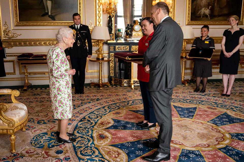 Queen Elizabeth II presents the George Cross to Peter May, Permanent Secretary at the Department of Health and Chief Executive of Health and Social care, and Sister Joanna Hogg, Royal Victoria Hospital Emergency Department, representatives of Britain's National Health Service (NHS), during an Audience at Windsor Castle, west of London on July 12, 2022. - Queen Elizabeth II praised Tuesday the "amazing" Covid-19 vaccine rollout, awarding the National Health Service (NHS) the George Cross