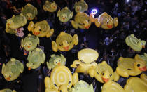 Inflatable yellow ducks, which have become good-humored symbols of resistance during anti-government rallies, are lifted over a crowd of protesters Friday, Nov. 27, 2020 in Bangkok, Thailand. Pro-democracy demonstrators are continuing their protests calling for the government to step down and reforms to the constitution and the monarchy, despite legal charges being filed against them and the possibility of violence from their opponents or a military crackdown. (AP Photo/Sakchai Lalit)