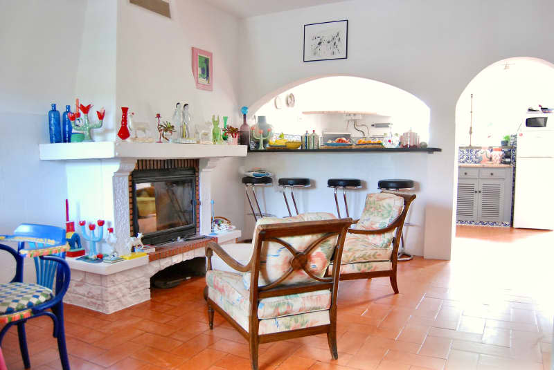 Chairs in front of fireplace accessorized with candle holders, vases, and other decor in white room.