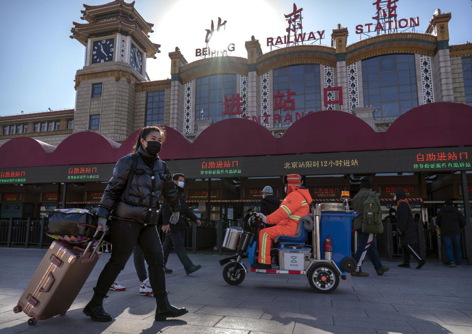 Travelers wearing face masks to protect against the spread of the coronavirus walk with their luggage at the Beijing Railway Station in Beijing, Thursday, Jan. 28, 2021. Efforts to dissuade Chinese from traveling for Lunar New Year appeared to be working. Beijing's main train station was largely quiet on the first day of the travel rush and estimates of passenger totals were smaller than in past years. (AP Photo/Mark Schiefelbein)