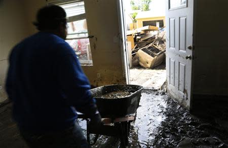 A man carries mud out of a home damaged by a flood using a wheelbarrow in Evans, Colorado September 23, 2013. REUTERS/Rick Wilking