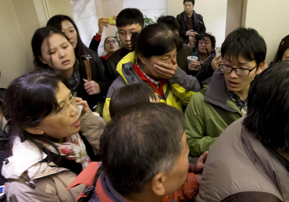 A woman, center, surrounded by media covers her mouth on her arrival at a hotel which is prepared for relatives or friends of passengers aboard a missing airline, in Beijing, China Saturday, March 8, 2014. A Malaysia Airlines Boeing 777-200 carrying 239 people lost contact over the South China Sea early Saturday morning on a flight from Kuala Lumpur to Beijing, and international aviation authorities still hadn't located the jetliner several hours later. (AP Photo/Andy Wong)