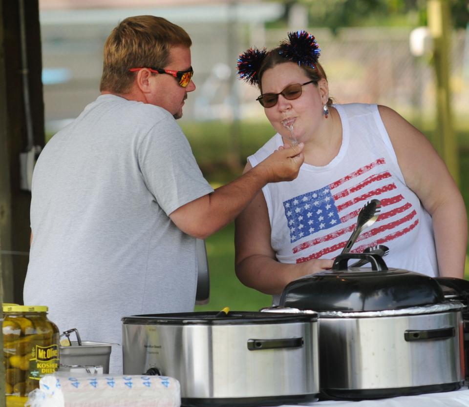 Rachal Helmick samples a bite of turkey July 4, 2021, from Robert Helmick at the Sebring Music Boosters' booth during the Fourth of July celebration at the Sebring Community Center. This year's activities will be held at Southside Park in the village.