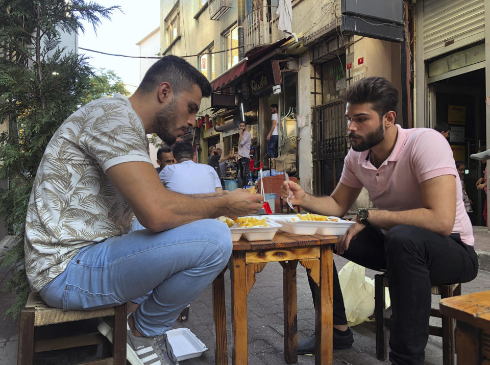 In this photo taken on July 31, 2019, Yousef Abbas, left, and his friend Fadi Farousi, both from Syria, pass time at an Istanbul neighbourhood where many Syrians live. Abbas from Aleppo, is registered in the city of Izmir, Turkey but works in Istanbul's vast tourism sector. "I am afraid. I don't go out. Why? Because I would get caught," he says. Syrians say Turkey has been detaining and forcing some Syrian refugees to return back to their country the past month.(AP Photo/Mehmet Guzel)
