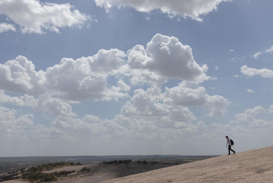 A visitor hikes downward from Enchanted Rock's summit at Enchanted Rock State Natural Area, located north of Fredericksburg, on a hot summer day, July 26, 2023.