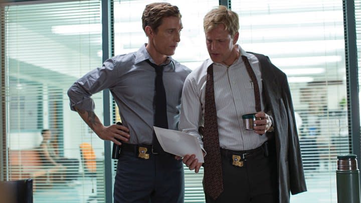 Matthew McConaughey and Woody Harrelson standing in an office in True Detective.