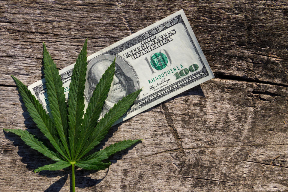 A marijuana leaf on top of a hundred dollar bill.