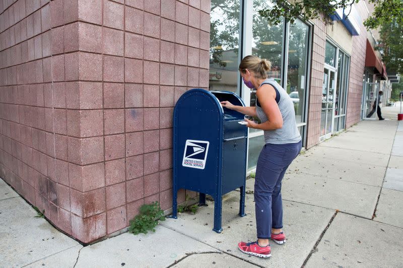 An individual deposits letters into a U.S. Postal Service (USPS) collection mailbox in Philadelphia