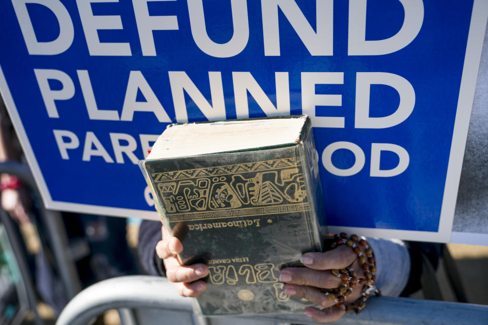 <p>A woman holds rosary beads, a bible, and an Anti-abortion sign as she attends a rally on the National Mall in Washington, Friday, Jan. 19, 2018, during the annual March for Life. (Photo: Andrew Harnik/AP) </p>