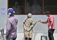 Paramedics check the oxygen saturation level of a suspected COVID-19 patient, center, at a government run hospital in Jammu, India, Friday, May 7, 2021. With coronavirus cases surging to record levels, Indian Prime Minister Narendra Modi is facing growing pressure to impose a harsh nationwide lockdown amid a debate whether restrictions imposed by individual states are enough. (AP Photo/Channi Anand)