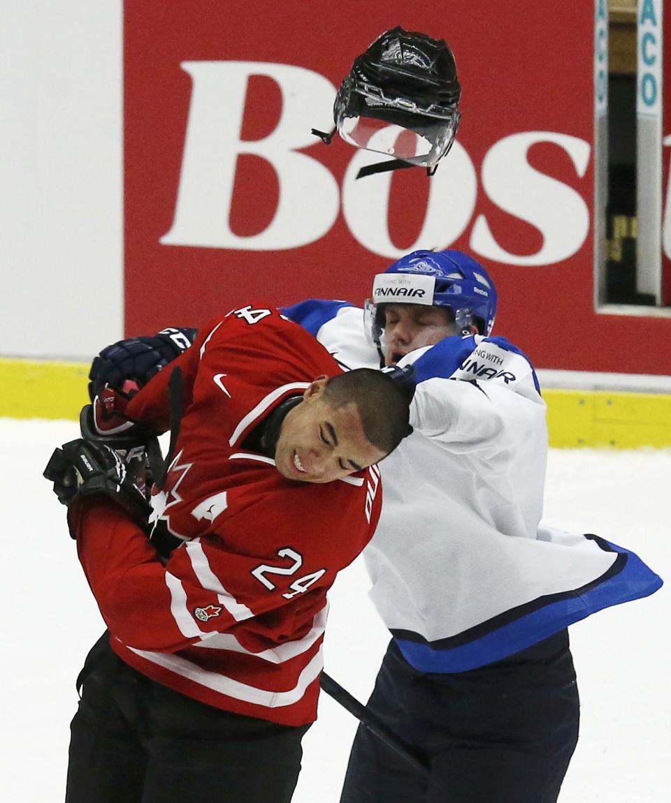 Canada's Mathew Dumba (L) loses his helmet after being hit by Finland's Aleksi Mustonen during the third period of their IIHF World Junior Championship ice hockey game in Malmo, Sweden, January 4, 2014. REUTERS/Alexander Demianchuk (SWEDEN - Tags: SPORT ICE HOCKEY)