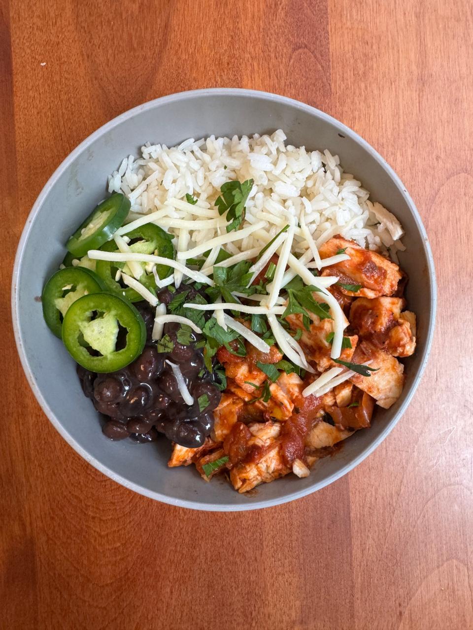 A bowl of rice, jalapenos, beans, chicken and cilantro