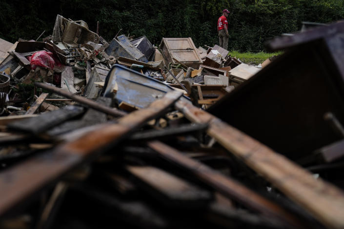 FILE - A man stands near a pile of debris as residents start to clean up and rebuild in Fleming-Neon, Ky., Aug. 5, 2022, after massive flooding the previous week. Costly weather disasters kept raining down on America last year, pounding the nation with 18 climate extremes that caused at least $1 billion in damage each, totaling more than $165 billion, federal climate scientists calculated Tuesday, Jan. 10, 2023. (AP Photo/Brynn Anderson, File)