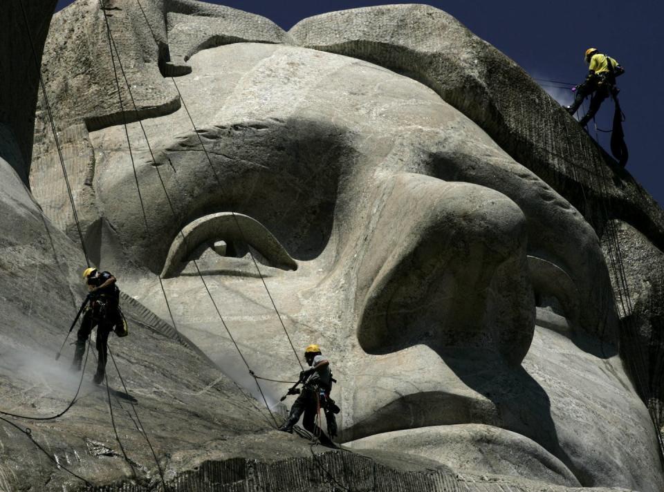 Des ouvriers utilisent des nettoyeurs à pression pour nettoyer le visage de Thomas Jefferson au mémorial national du Mont Rushmore dans le Dakota du Sud. (AP Photo/Charlie Riedel)