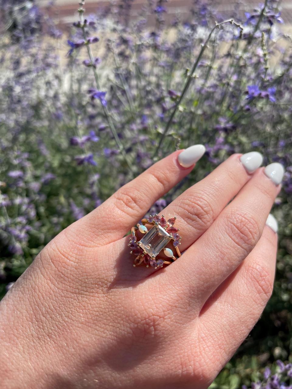 photo of a hand with a ring on it and flowers on the background (Abby Leach)