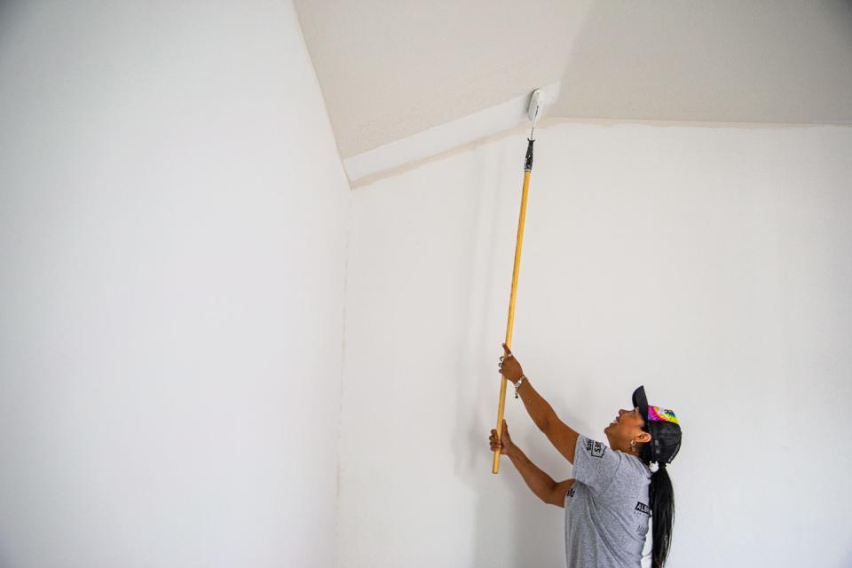 Irma Garcia helps paint the living room ceiling of her two-bedroom, one-bathroom home by Habitat for Humanity on May 19, 2022, in Corpus Christi, Texas.