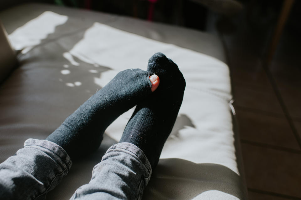 Person's feet in black socks and gray pants lounging comfortably on a couch