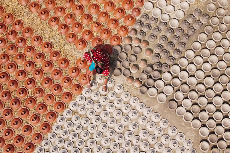 Una mujer arregla ollas de barro antes de ser transportadas para venderlas en un mercado en Brahmanbaria, Bangladesh.