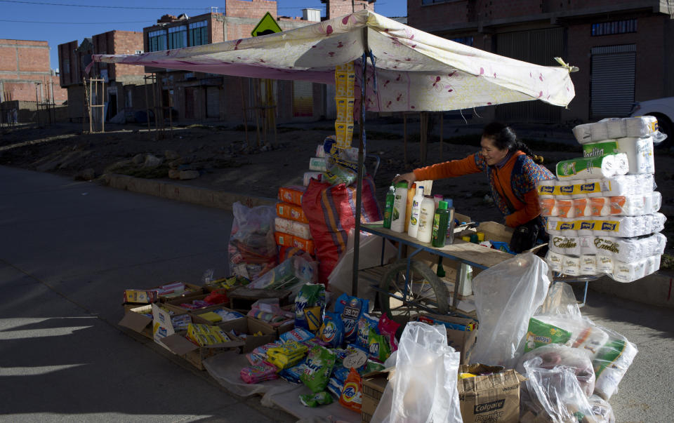 En esta imagen del 15 de mayo de 2019, la vendedora y actriz Carmen Aranibar, de la compañía teatral "Kory Warmis", o Mujeres de Oro, coloca los productos en su puesto en una avenida de El Alto, Bolivia. (AP Foto/Juan Karita)