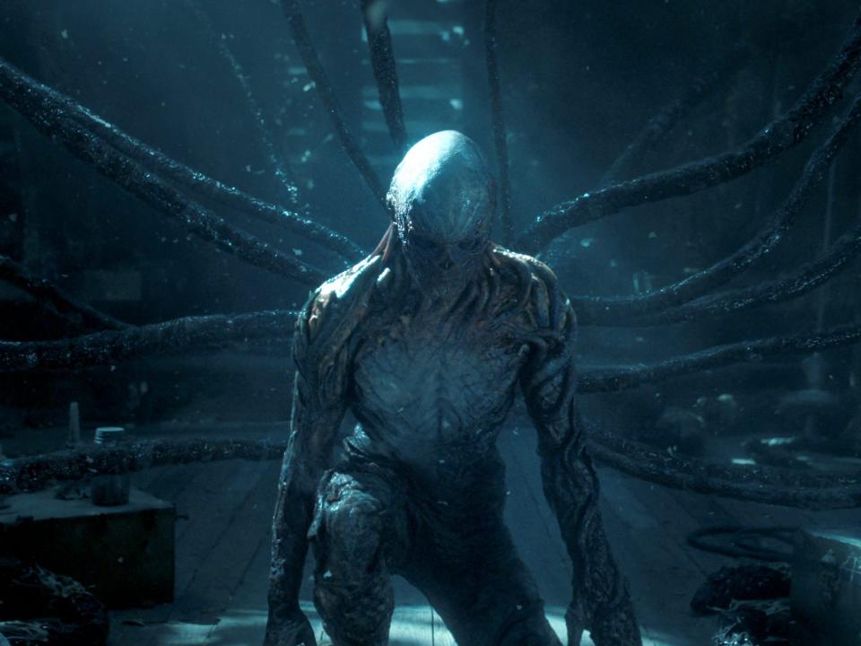 A humanoid creature with gray skin kneels in an attic.