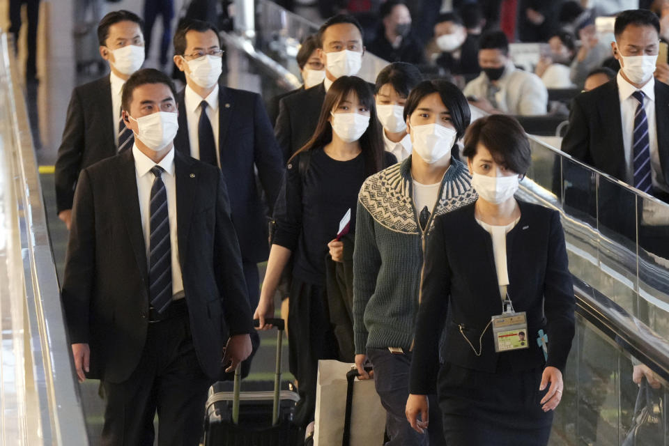 Japan's former Princess Mako, fourth right, the elder daughter of Crown Prince Akishino, and her husband Kei Komuro, second right, are escorted to board an airplane to New York Sunday, Nov. 14, 2021, at Tokyo International Airport in Tokyo. (AP Photo/Eugene Hoshiko)