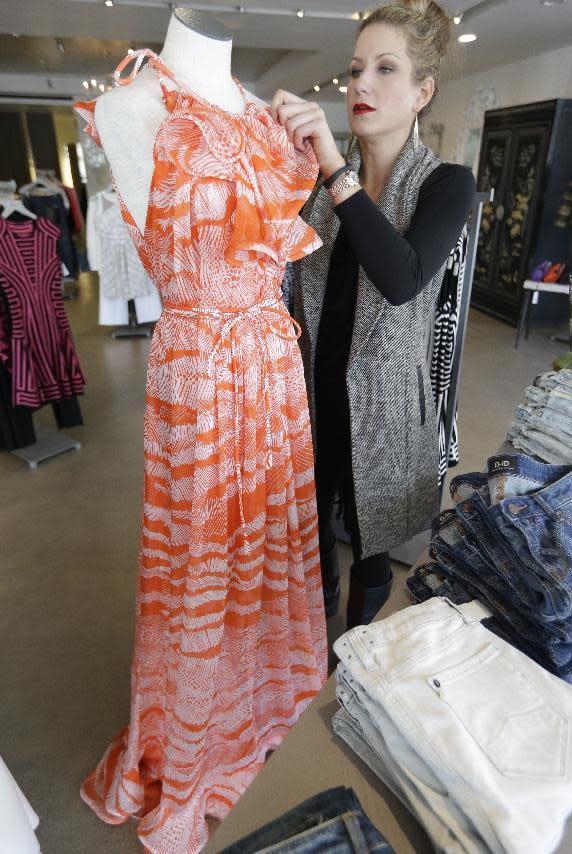 This March 6, 2014 photo shows senior stylist Tiffany Kimbrough adjusting a spring print dress on display at an Elements boutique in Dallas. “Women should look for pink in every shade,” said Ken Downing, fashion director of luxury chain Neiman Marcus, which has its flagship store downtown. He added those varying shades of pink can be worn all in one outfit. (AP Photo/LM Otero)