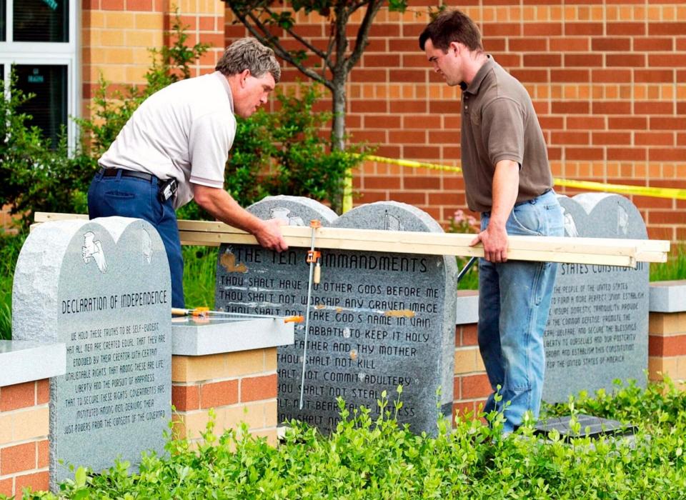 PHOTO: Workers remove a monument bearing the Ten Commandments outside West Union High School, June 9, 2003, in West Union, Ohio.  (Al Behrman/AP, FILES)