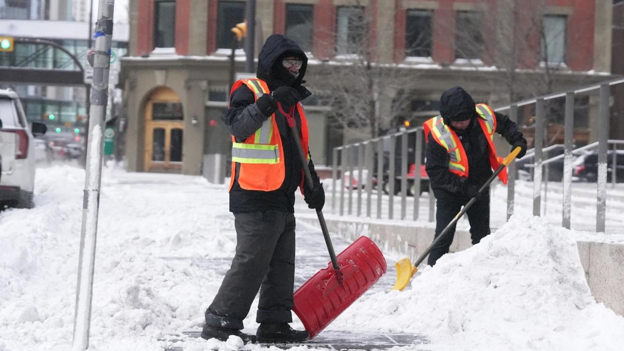 Workers shovel snow in Calgary on Jan. 10. Temperatures could reach –50 C with the wind chill over the weekend in Calgary and the surrounding area.  (Monty Kruger/CBC - image credit)