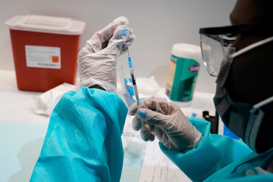 A health care worker fills a syringe with the Pfizer COVID-19  vaccine at the American Museum of Natural History in New York.
