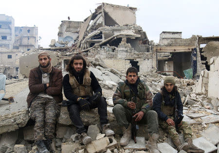 Rebel fighters sit on the rubble of damaged buildings as they wait to be evacuated from a rebel-held sector of eastern Aleppo, Syria December 16, 2016. REUTERS/Abdalrhman Ismail