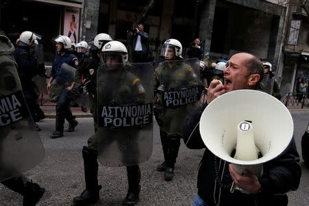 A demonstrator shouts slogans through a loudspeaker next to a riot police cordon during a protest against home auctions in Athens, Greece, March 14, 2018. REUTERS/Costas Baltas