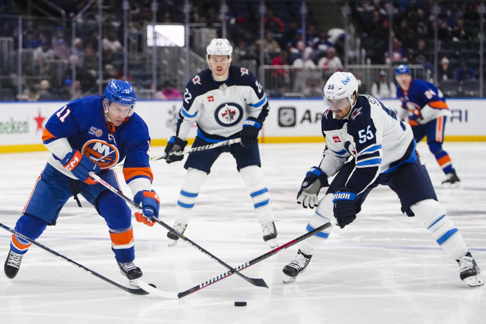 New York Islanders' Zach Parise (11) fights for control of the puck with Winnipeg Jets' Mark Scheifele (55) during the second period of an NHL hockey game Wednesday, Feb. 22, 2023, in Elmont, N.Y. (AP Photo/Frank Franklin II)